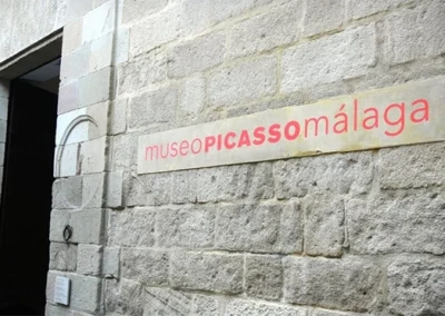 Entrada del Museo Picasso en Málaga, con rótulo sobre muro de piedra